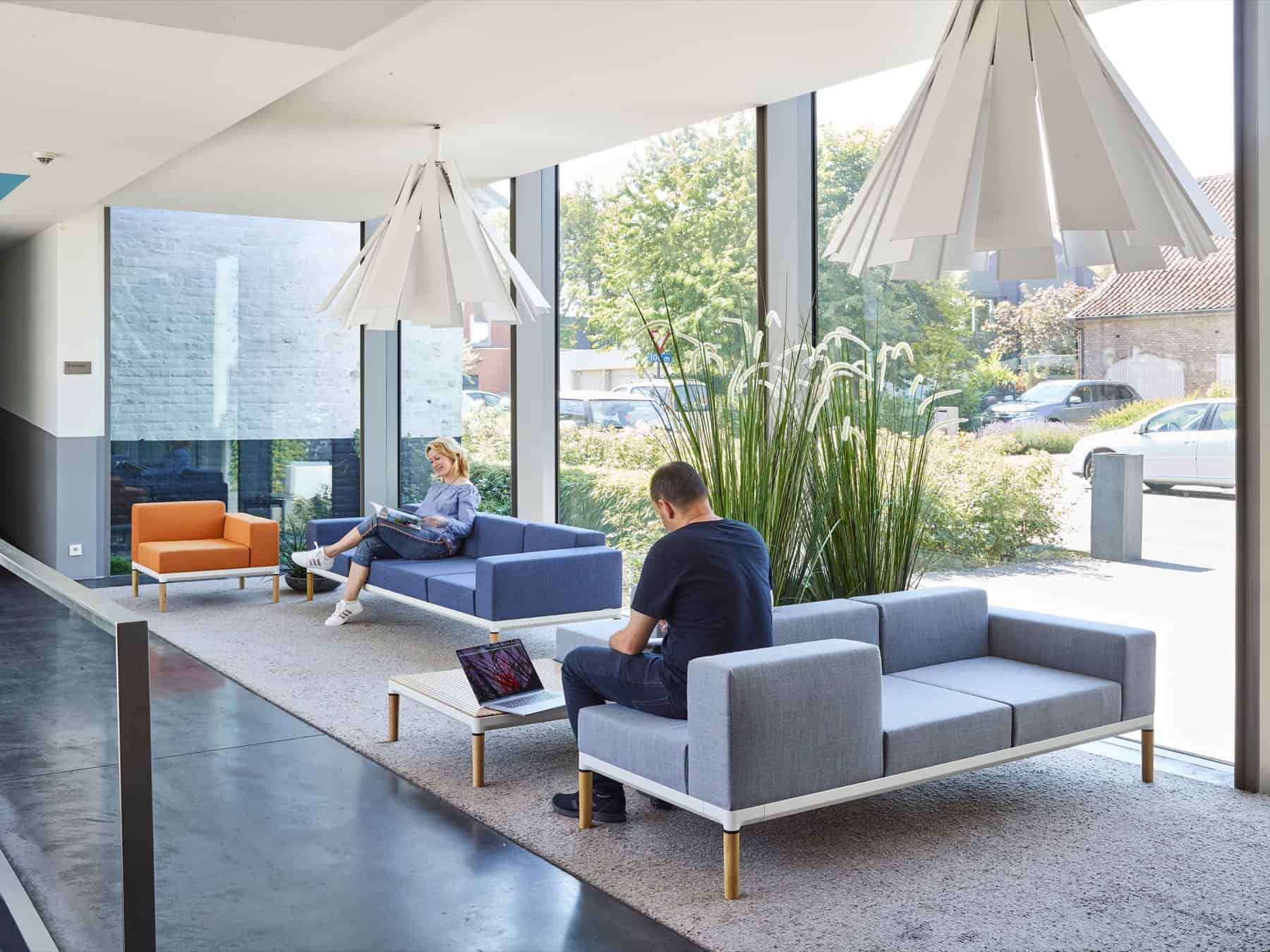 People seated on upholstered Nora sofas in a contemporary interior